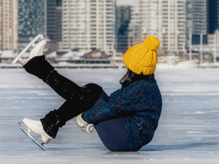 a person wearing figure skates sitting on a frozen lake
